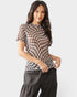 Woman wearing a checkered top and dark pants on a plain background