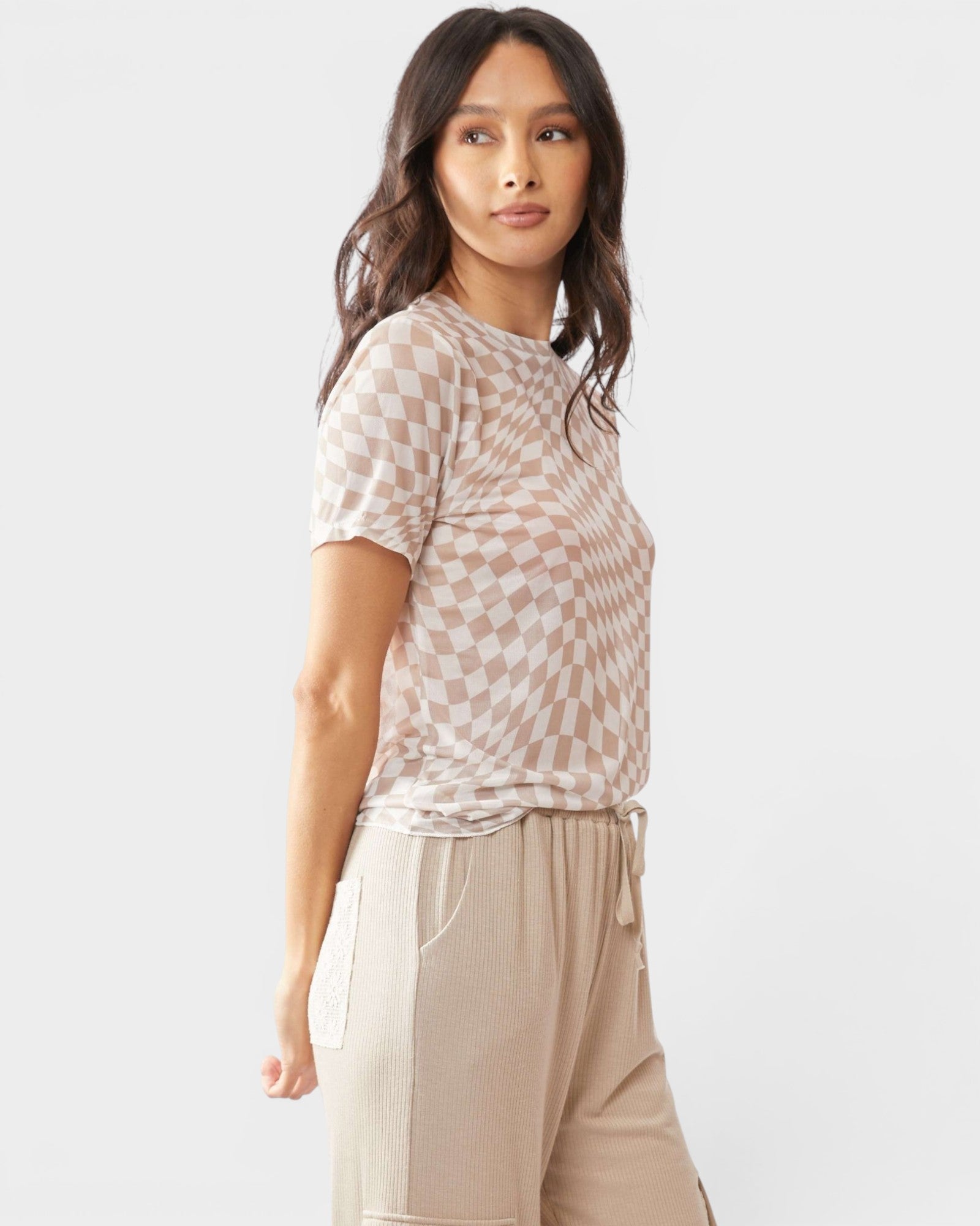 Woman wearing a checkered top and beige pants on a white background