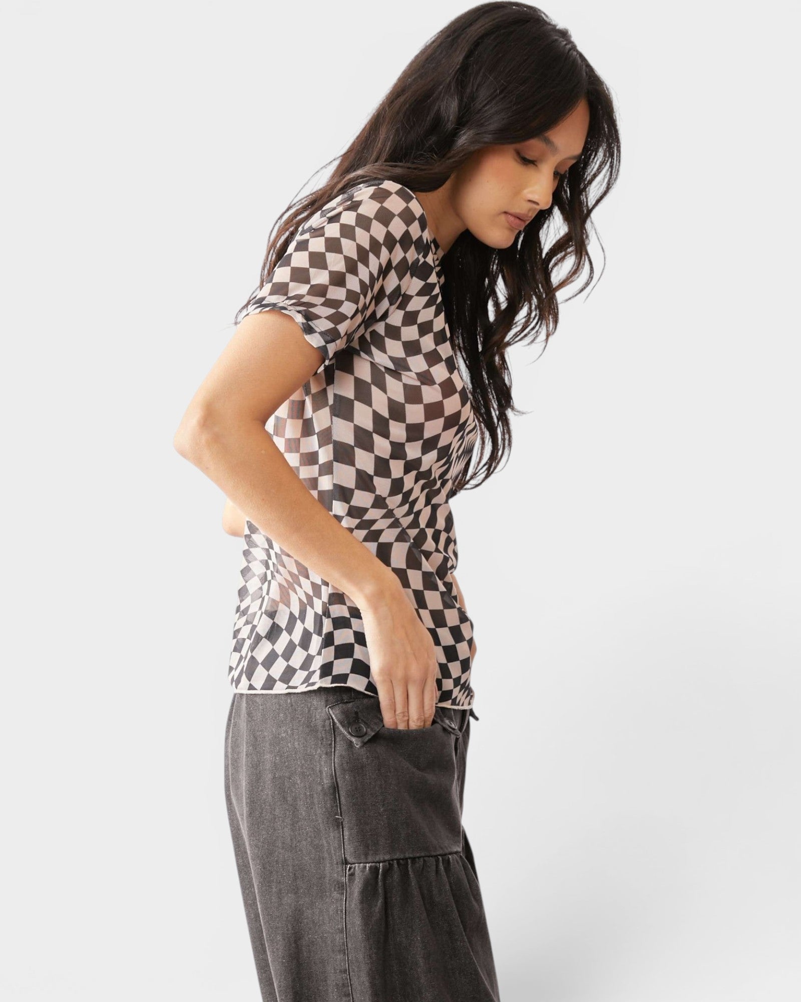 Woman wearing a checkered shirt and gray pants on a white background
