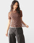 Woman wearing a checkered top and dark pants on a light background
