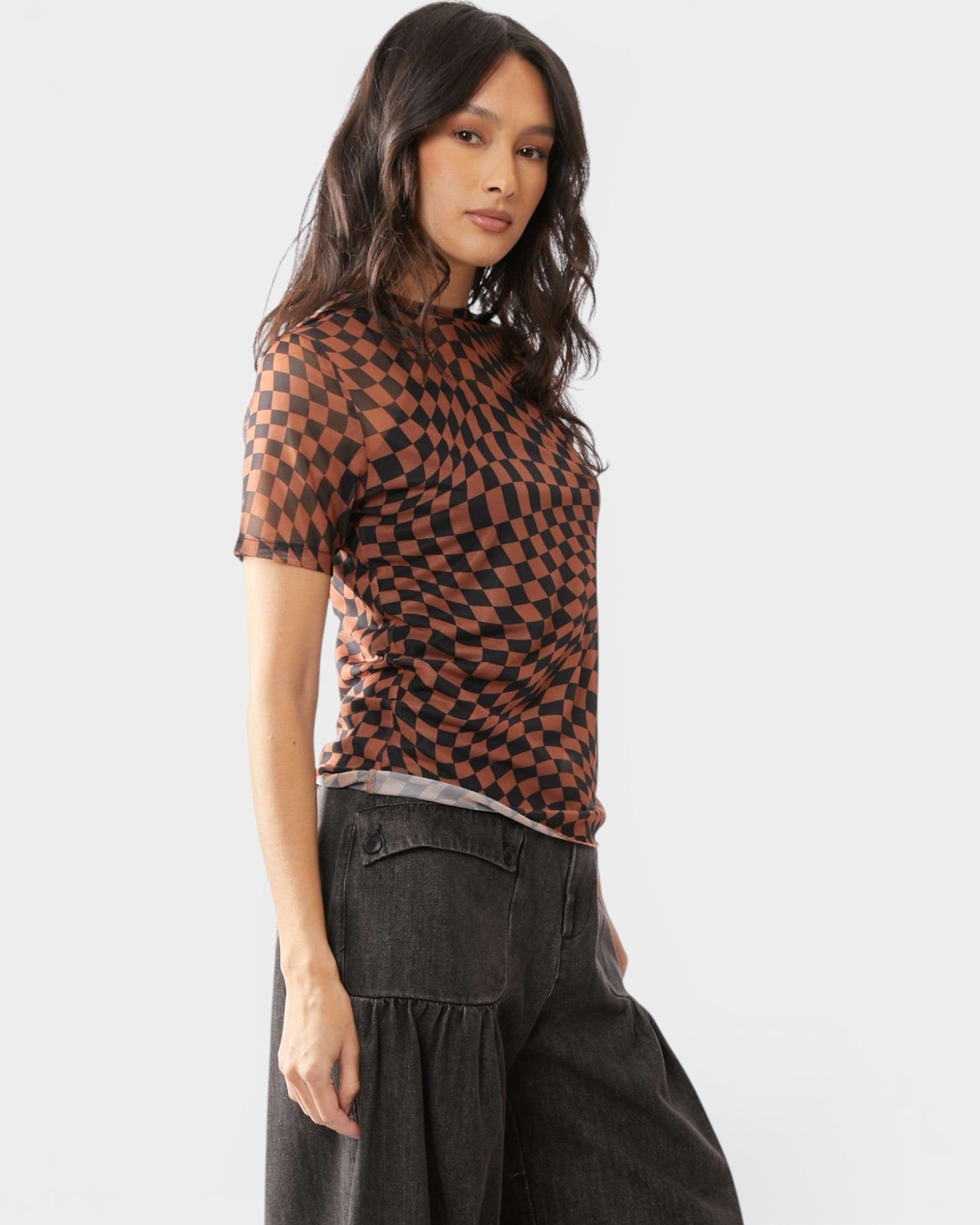 Woman wearing a patterned top and dark pants on a white background