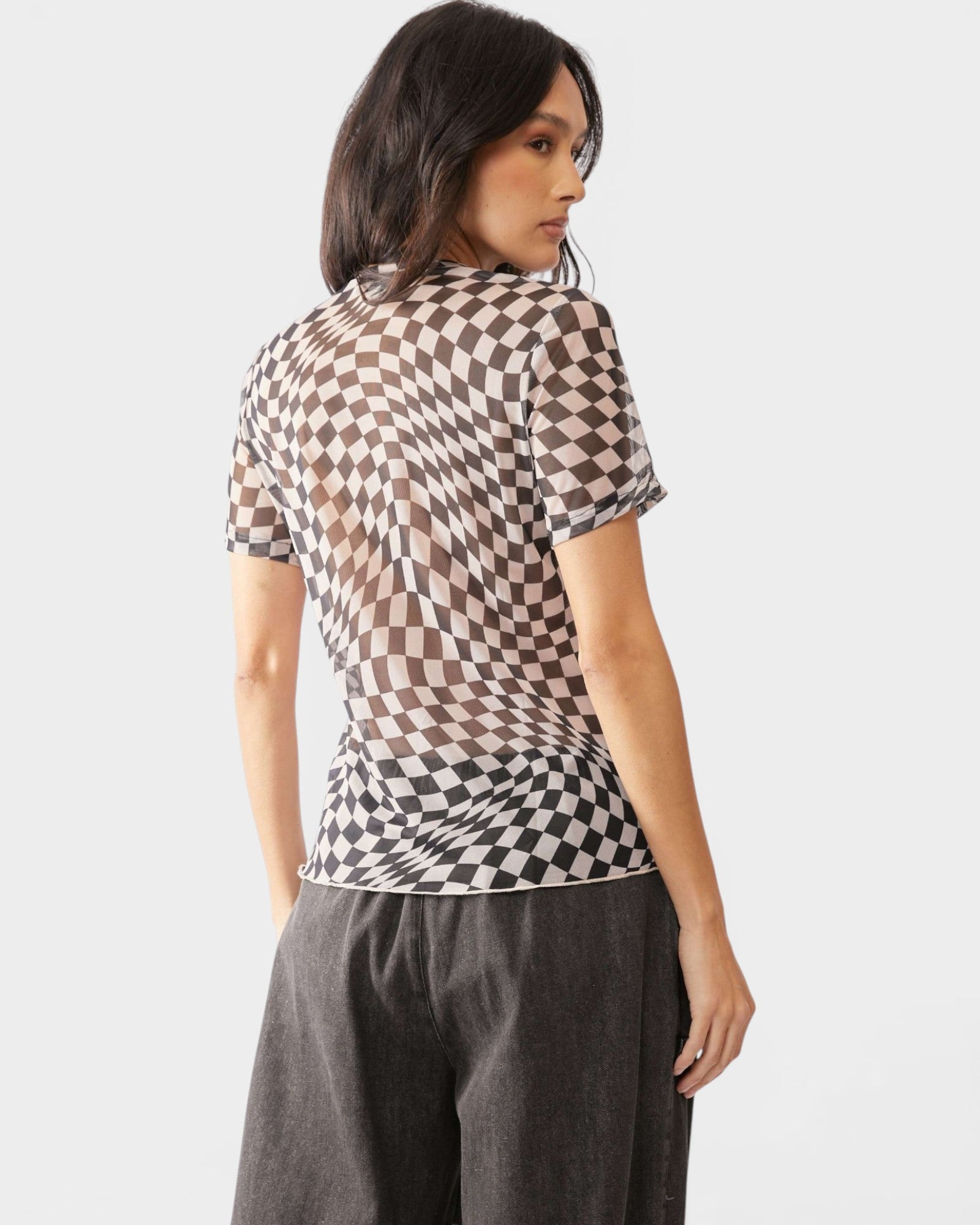 Woman wearing a checkered shirt with sheer panels on a white background