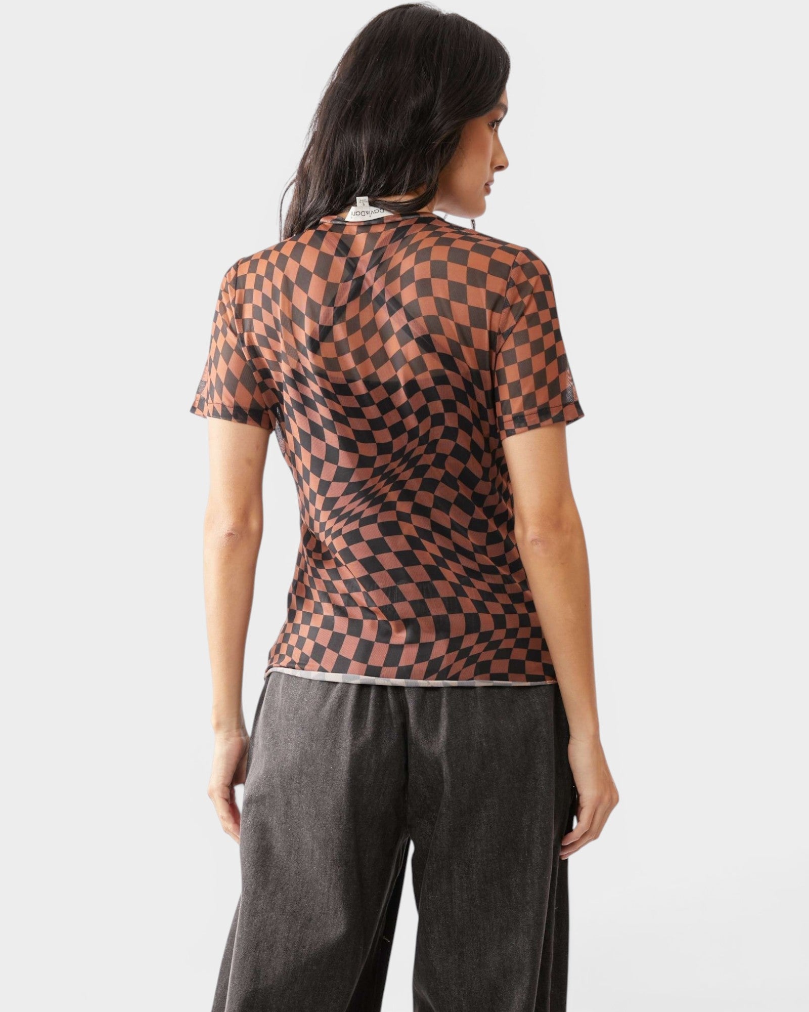 Woman wearing a brown and black checkered top with gray pants on a white background