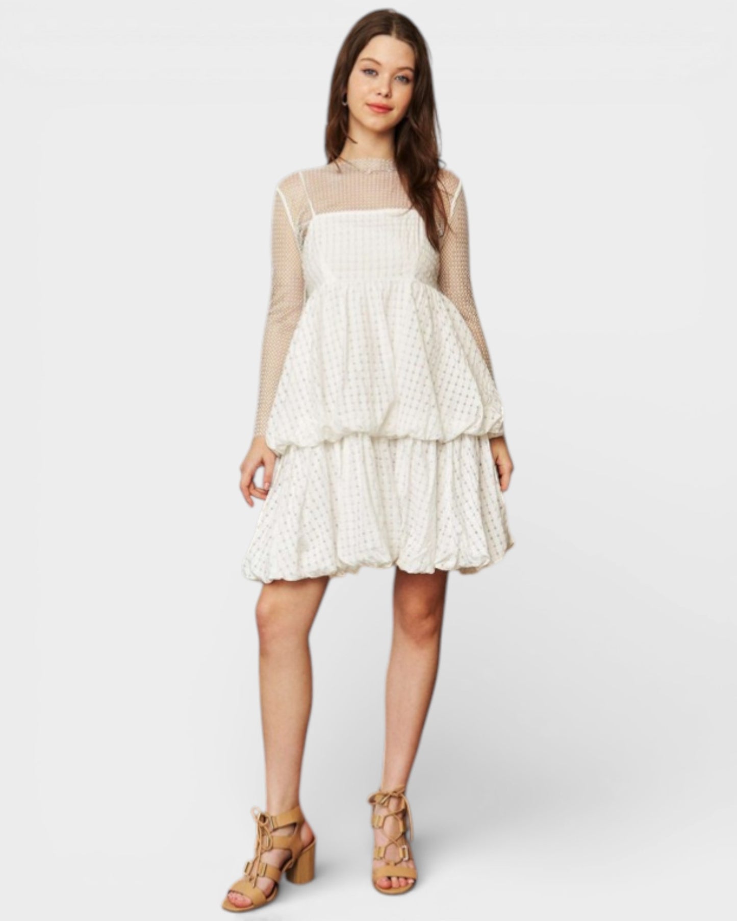 Woman wearing a white lace dress with sheer sleeves on a white background