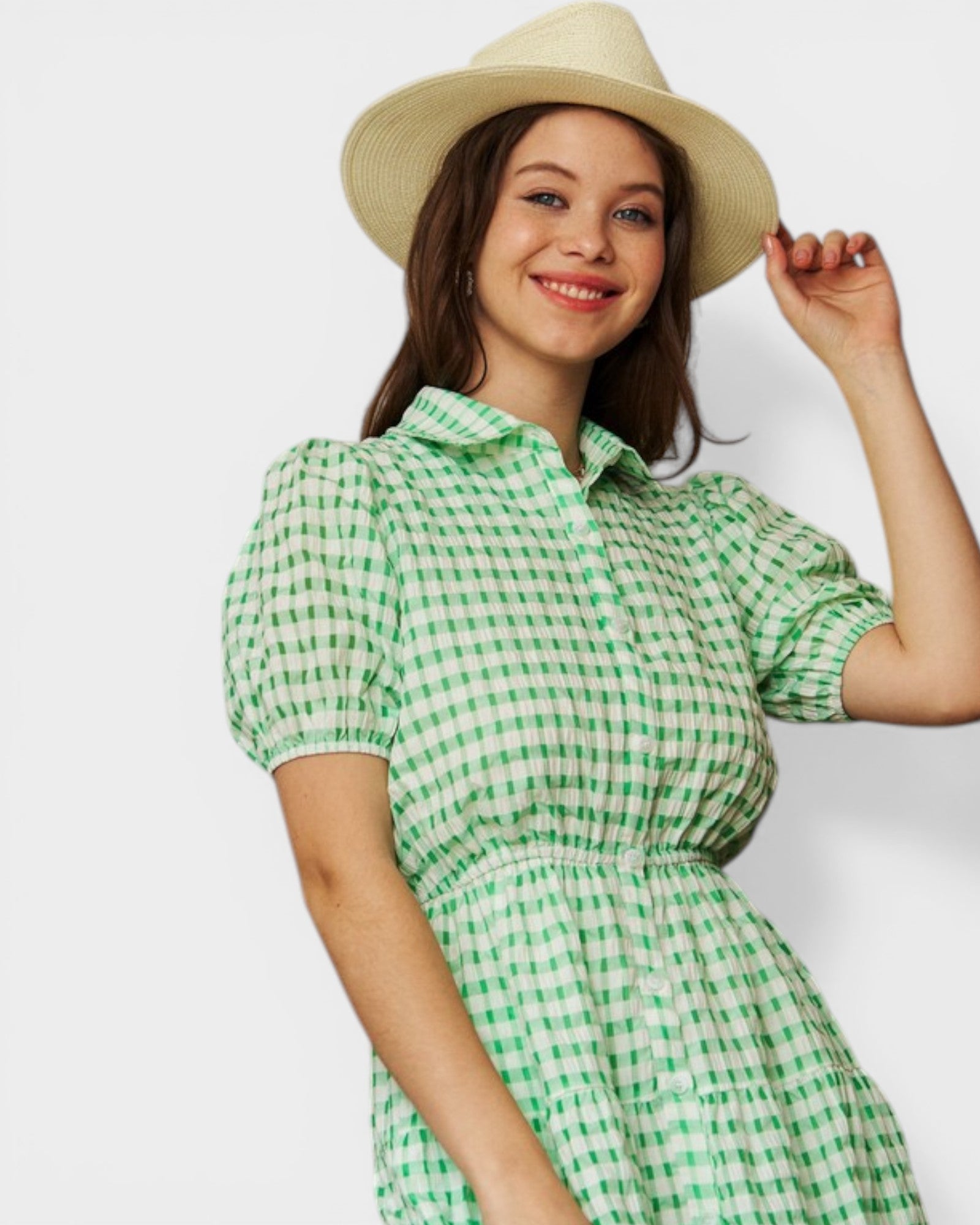 Woman wearing a green checkered dress and beige hat on a white background