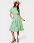 Woman wearing a green checkered dress with a white background