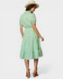 Woman wearing a green checkered dress and hat on a white background