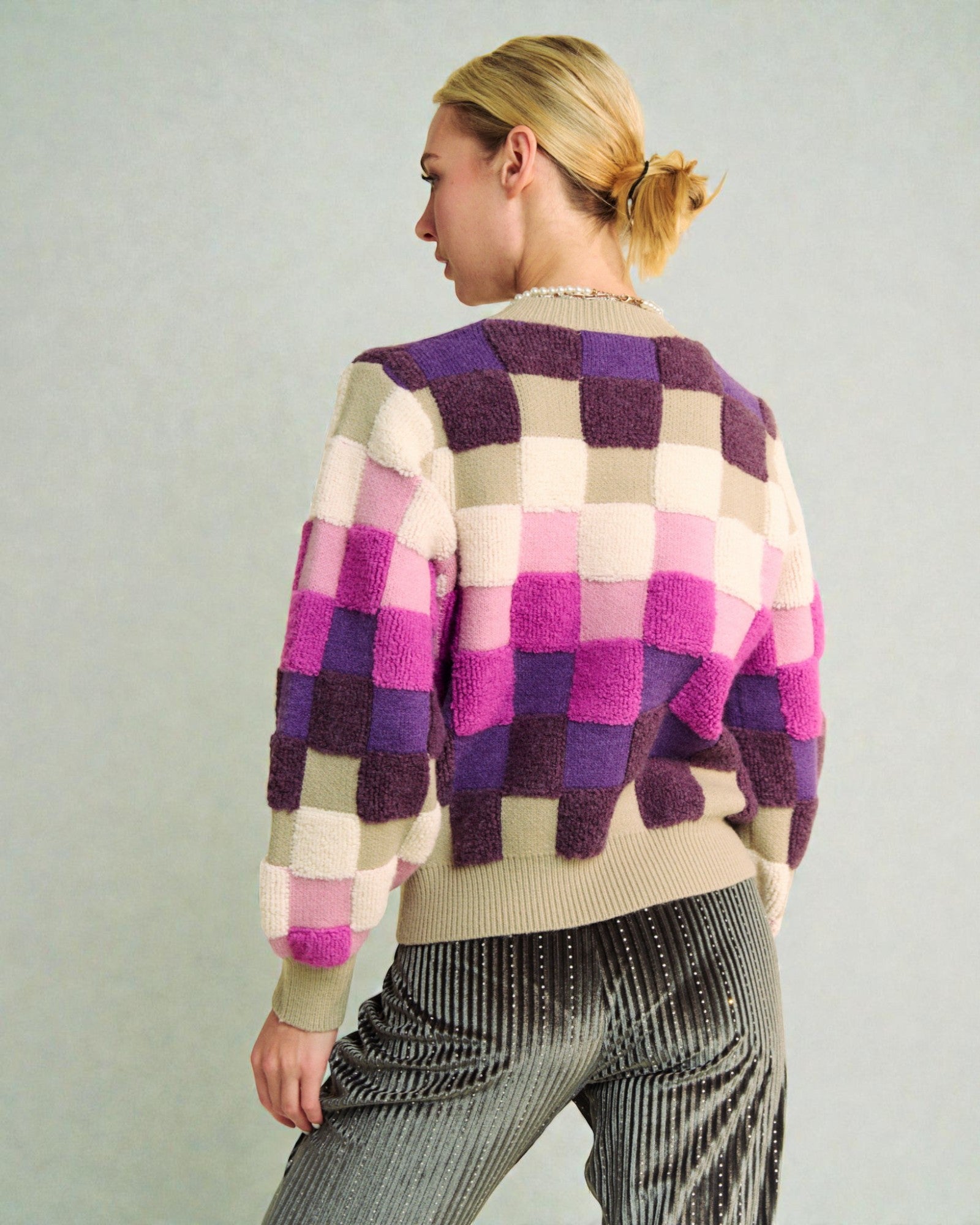 Woman wearing a colorful checkered sweater against a plain background