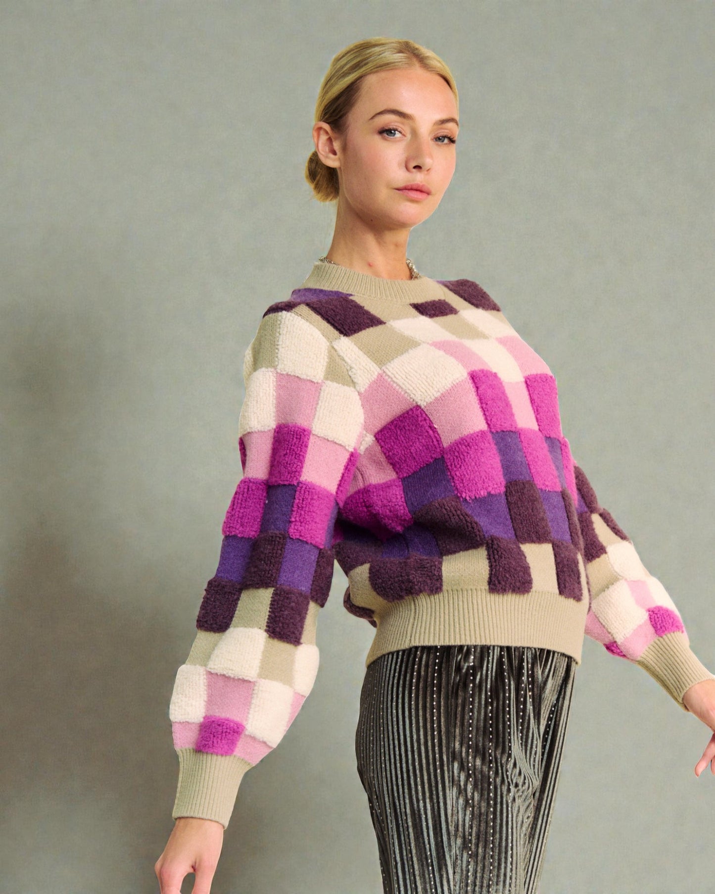 Woman wearing a colorful checkered sweater against a plain background