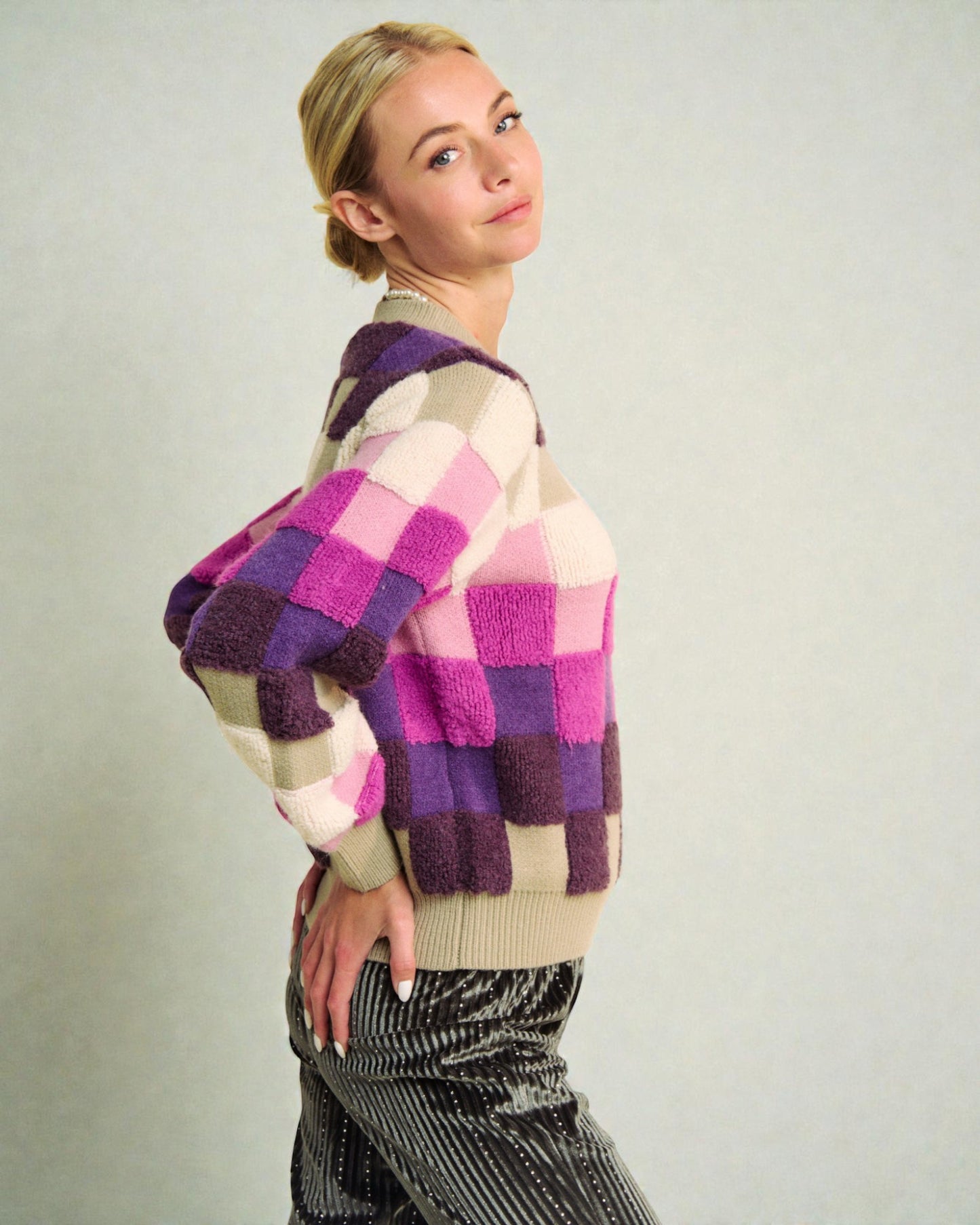 Person wearing a colorful checkered sweater against a plain background