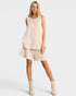 Woman wearing a beige sleeveless top and shorts set with matching boots on a white background