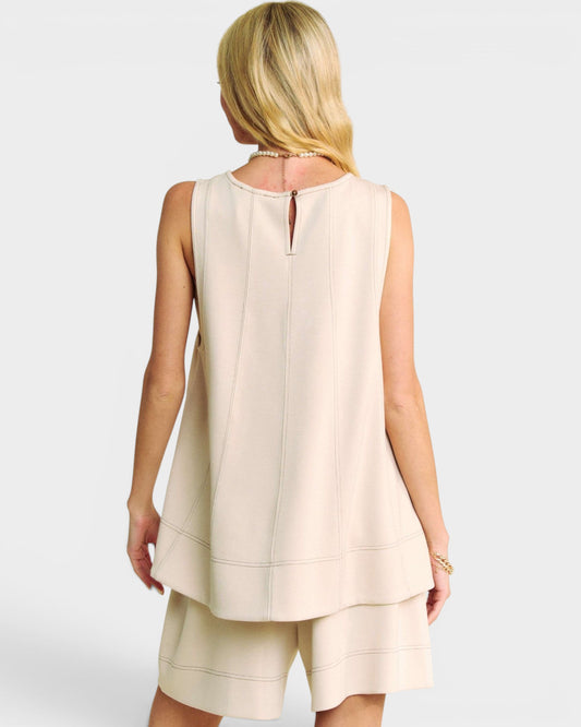 Woman wearing a beige sleeveless top and shorts set on a white background