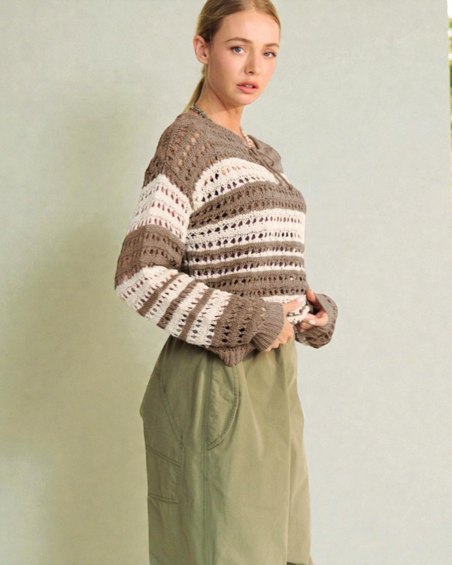 Woman wearing a brown and beige striped sweater against a plain background