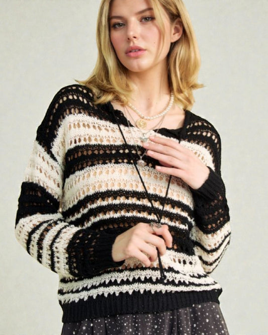 Woman wearing a black and white striped sweater against a plain background