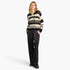 A woman modeling a black and cream striped knit sweater and matching black knit pants with small gold speckles, photographed against a light gray studio background.