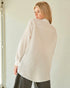 Woman wearing a beige oversized shirt against a plain background