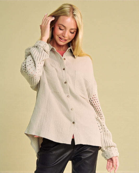 Woman wearing a beige button-up shirt with lace sleeves against a beige background