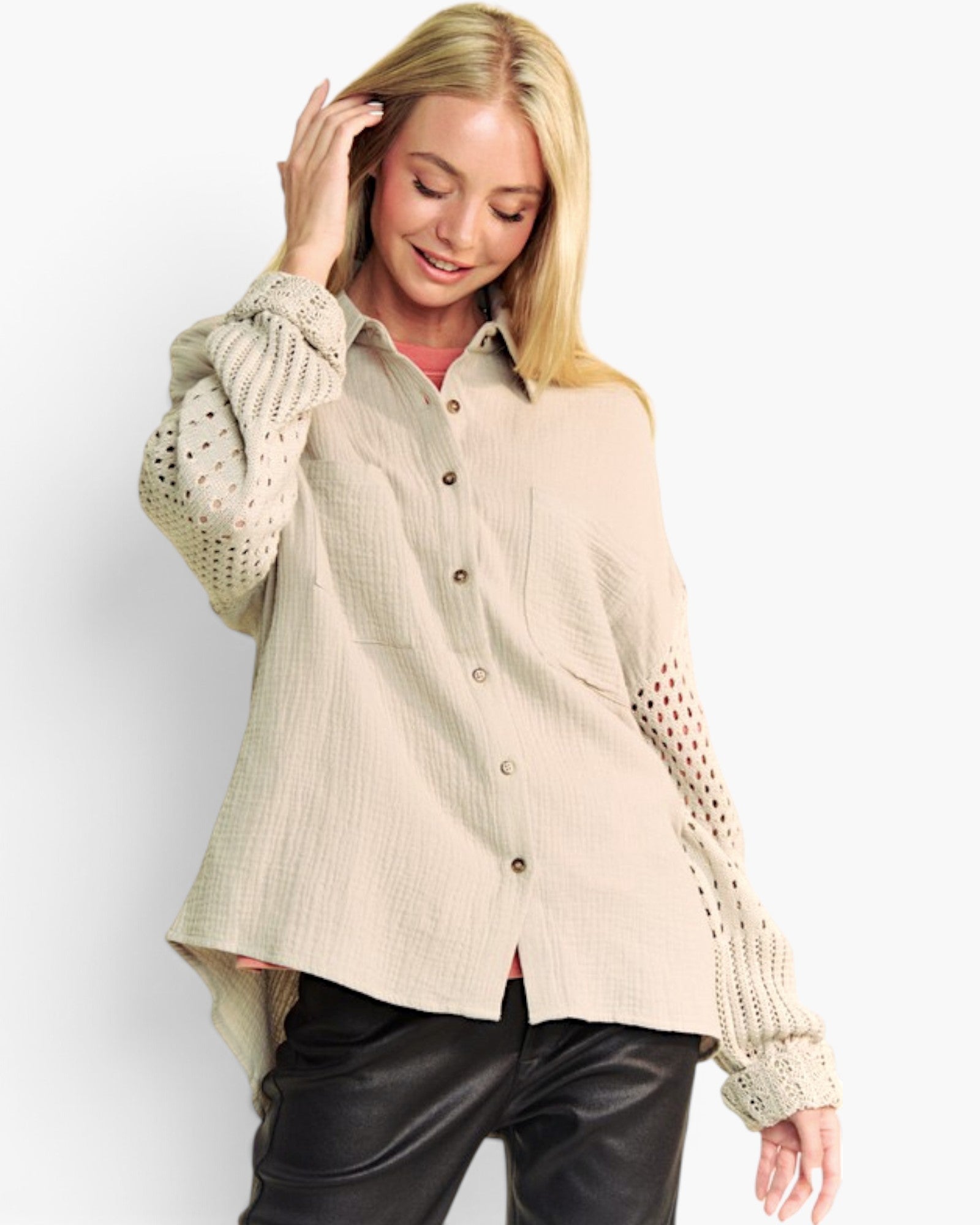 A woman modeling a light beige textured button-up shirt with distinctive open-knit sleeves, paired with black pants, against a plain white studio background.
