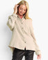 A woman modeling a light beige textured button-up shirt with distinctive open-knit sleeves, paired with black pants, against a plain white studio background.