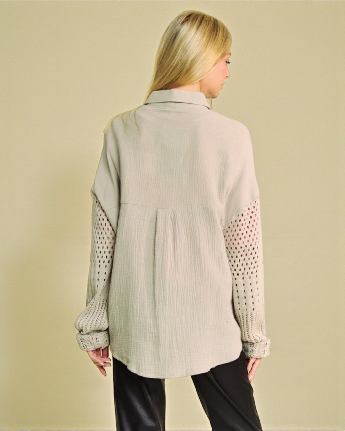 Woman wearing a beige shirt with patterned sleeves on a beige background