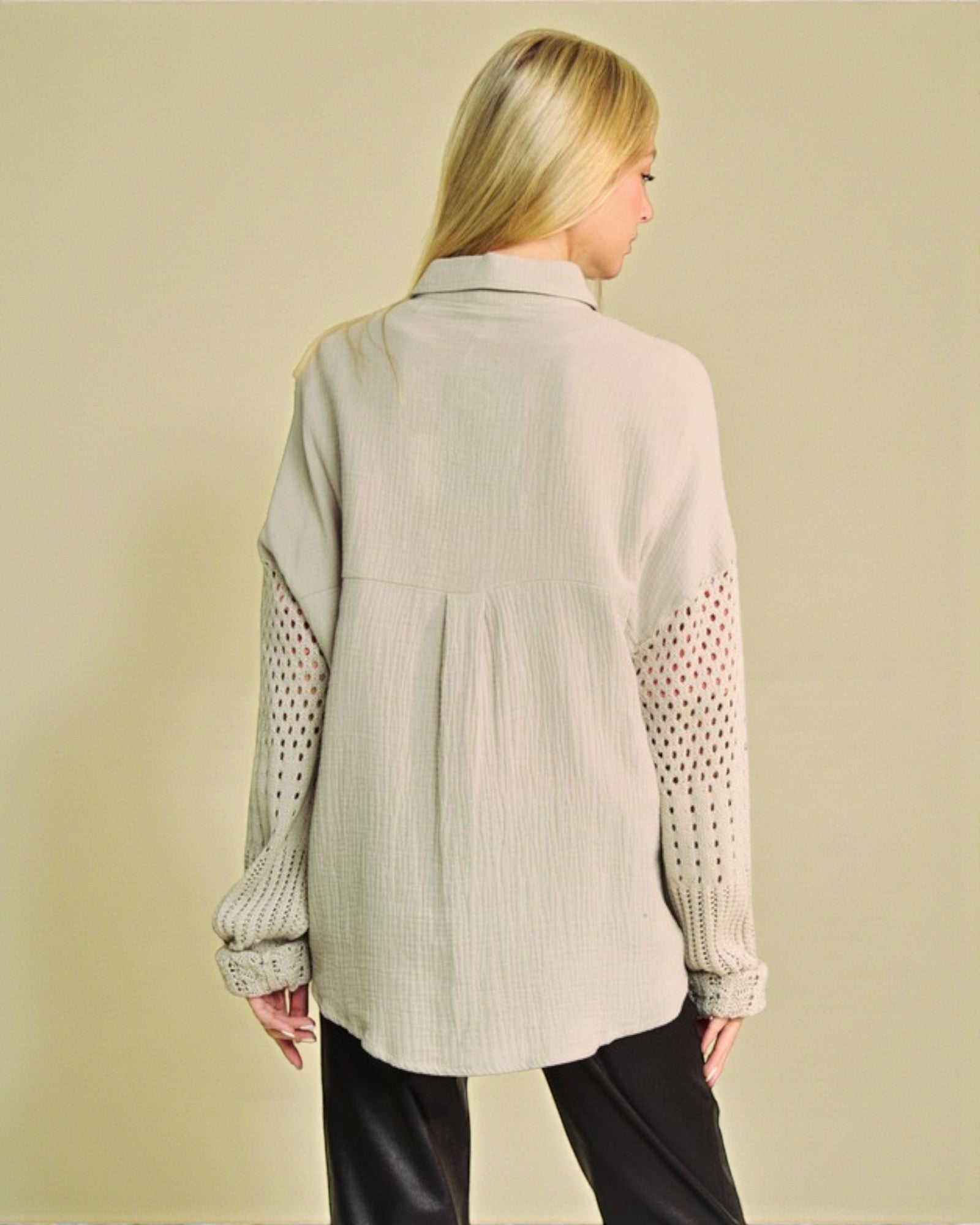 Woman wearing a beige shirt with patterned sleeves on a beige background