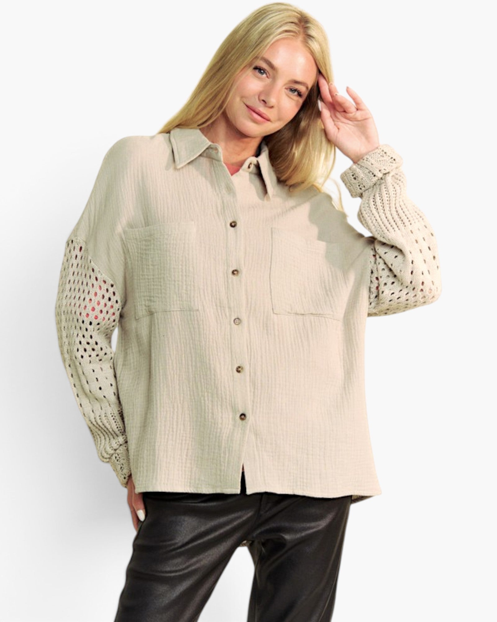 A woman modeling a light beige textured button-up shirt with knit cowl sleeves and black leather pants, photographed against a clean white studio background.