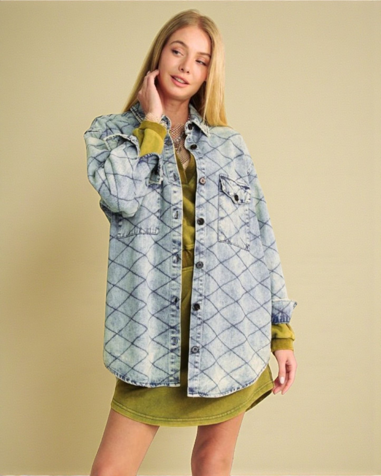 Woman wearing a denim jacket over a green dress on a beige background
