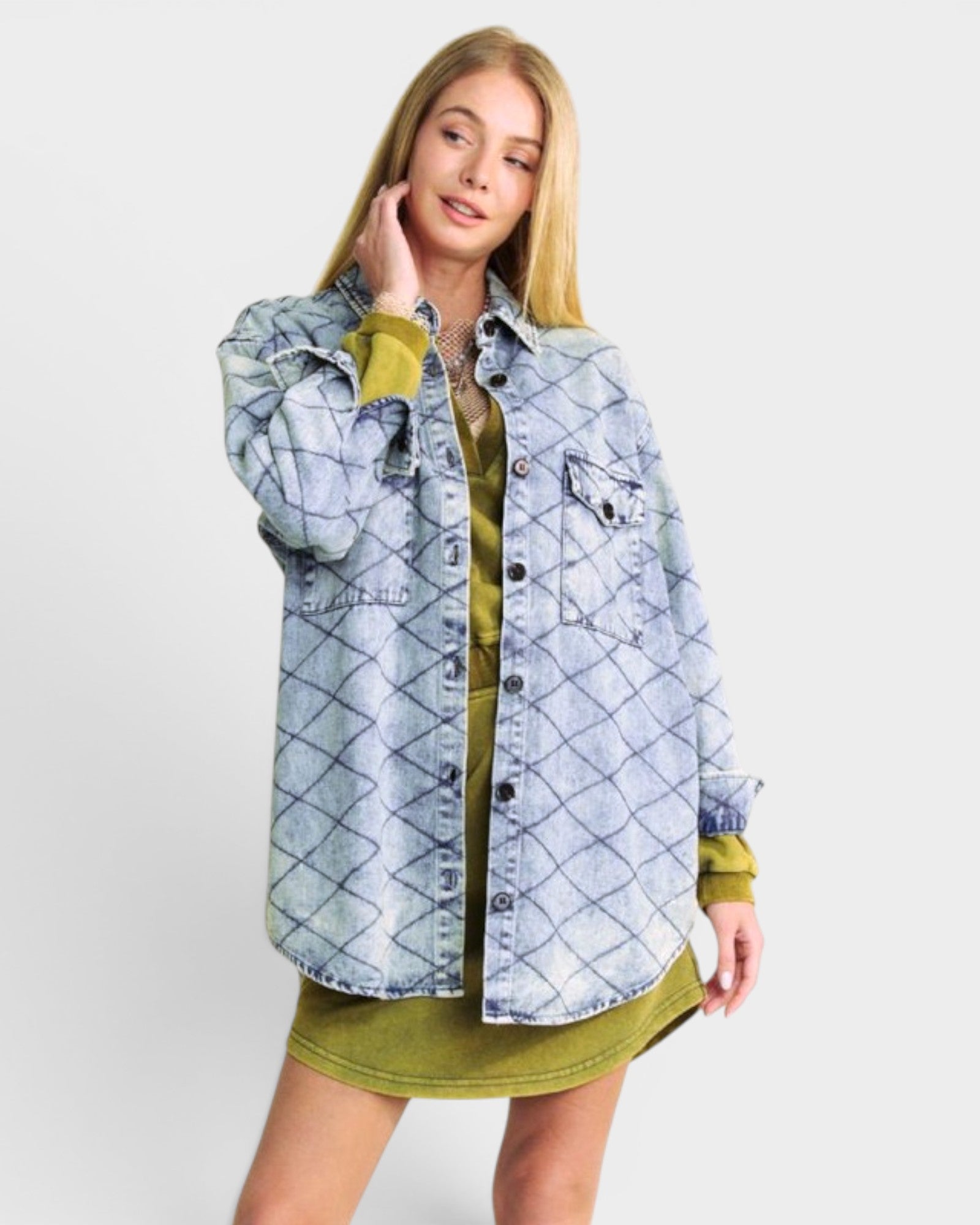 Woman wearing a light blue denim jacket over a green dress on a white background