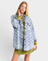 Woman wearing a light blue denim jacket over a green dress on a white background