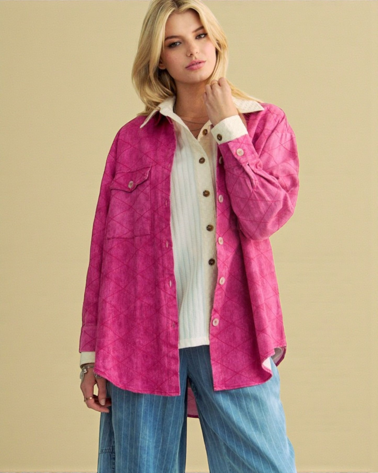 Woman wearing a pink jacket over a white shirt with a beige background