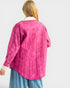 Person wearing a pink quilted jacket on a white background