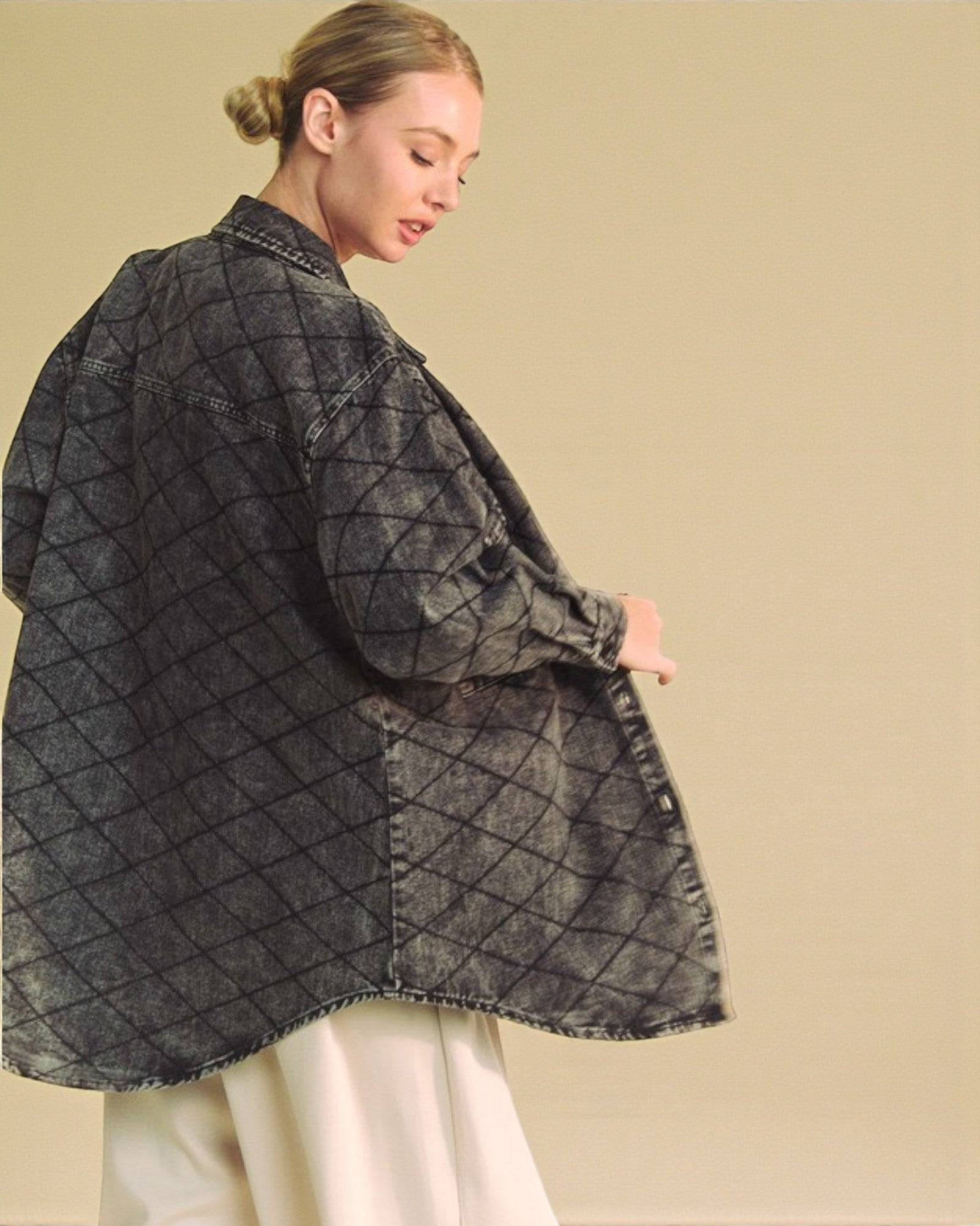 Woman wearing a dark denim jacket with a geometric pattern on a beige background
