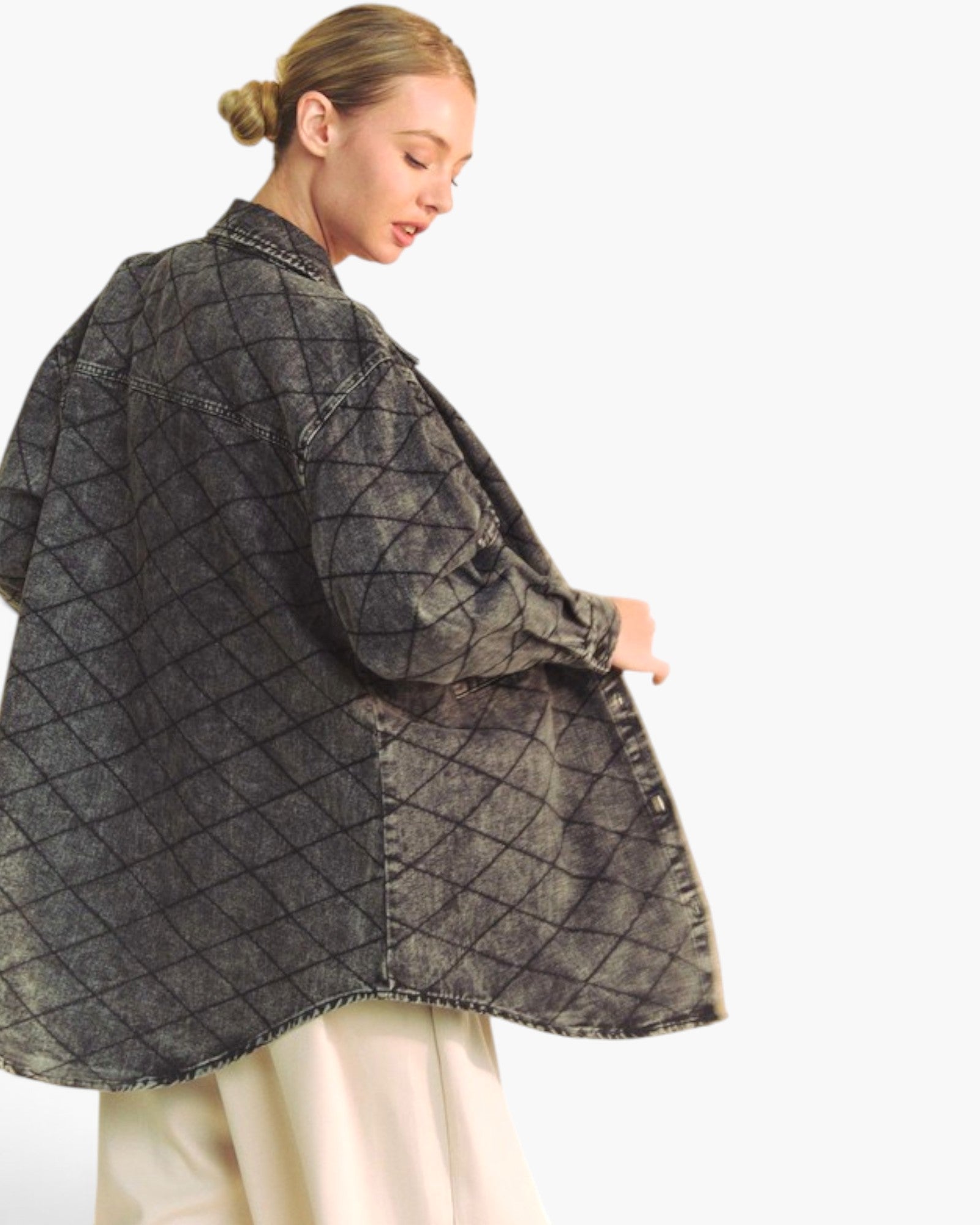 A woman wearing a dark gray washed denim jacket with a black diamond grid pattern, paired with cream-colored pants, shown from a side-back angle against a plain white background.