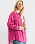 Woman wearing a pink jacket with a white collar on a plain background
