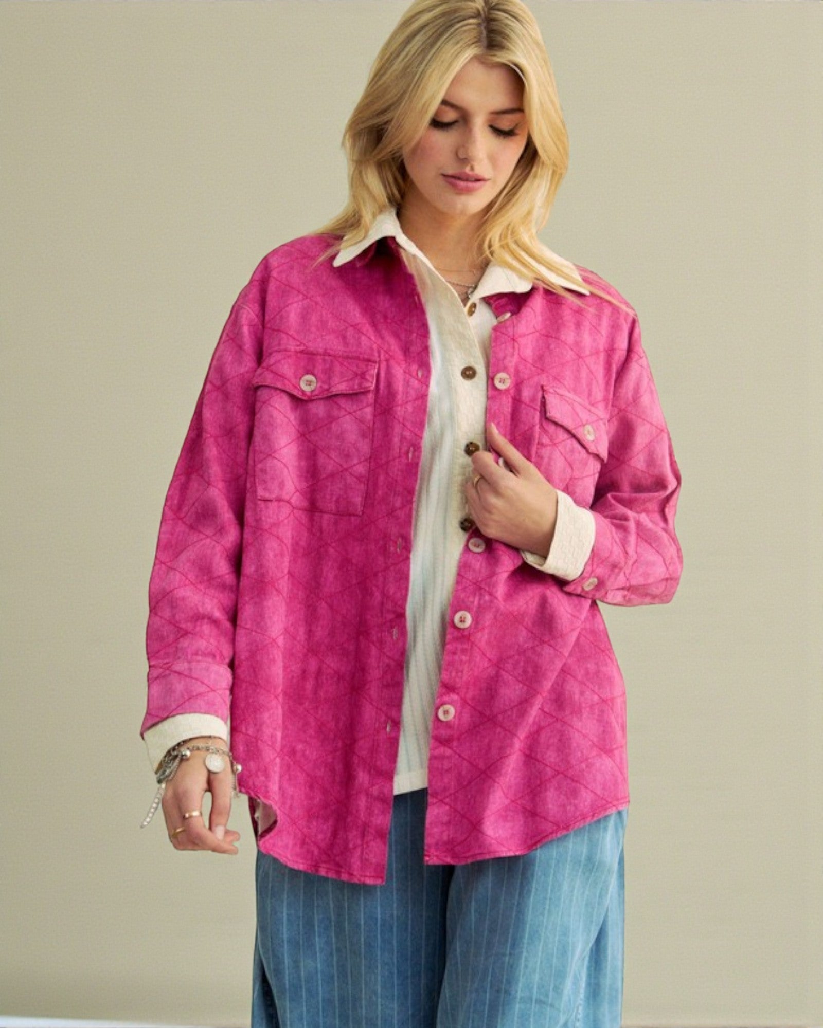 Woman wearing a bright pink jacket over a white shirt with a beige background