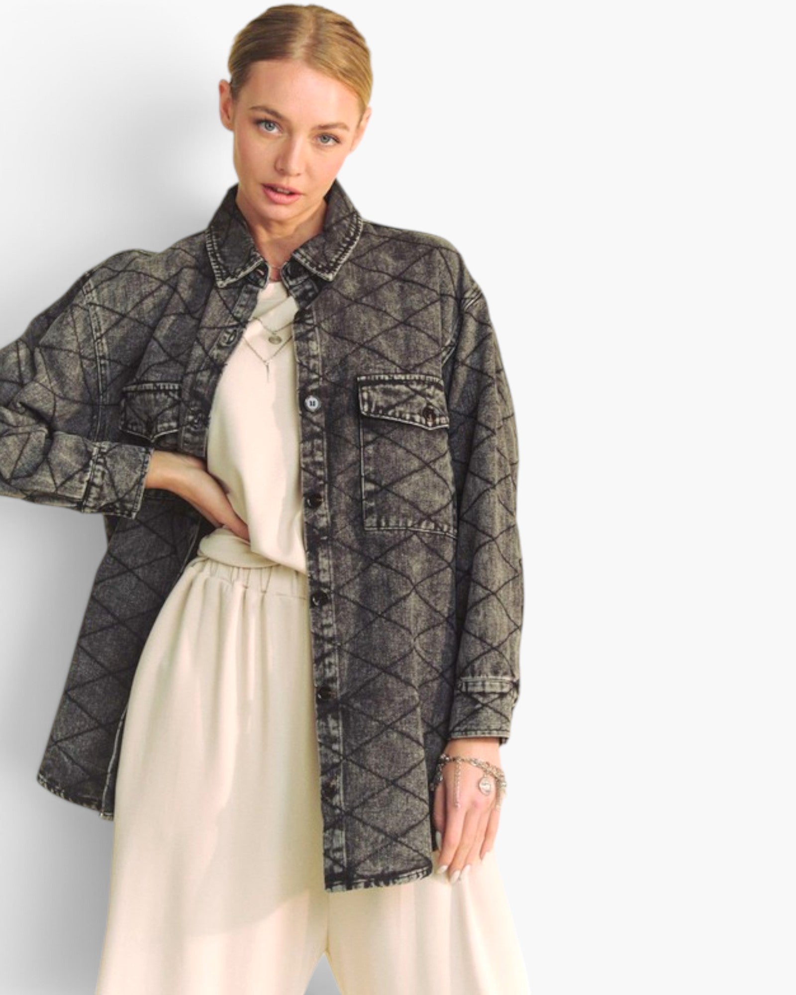 A woman models a dark gray quilted denim jacket over a cream-colored top and wide-leg trousers, set against a plain light gray studio background.
