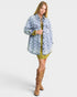 Woman wearing a denim jacket over a green dress with brown boots on a white background