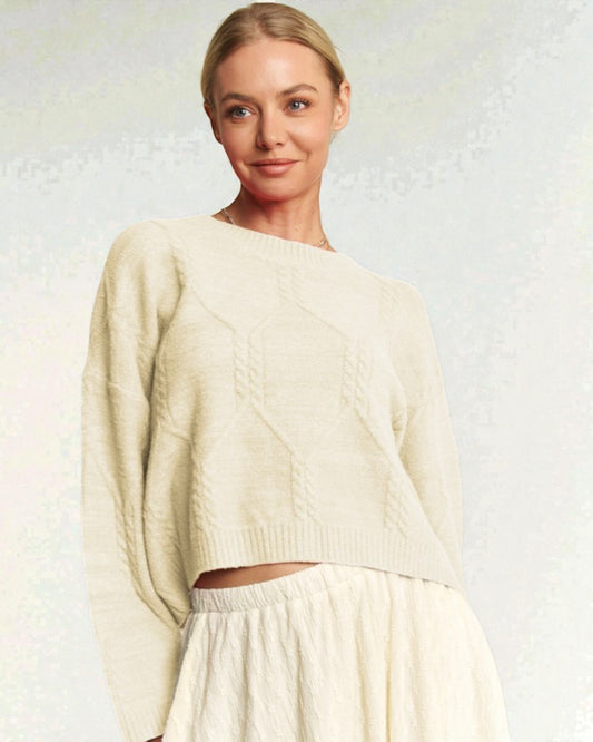 Woman wearing a cream sweater and skirt against a light background
