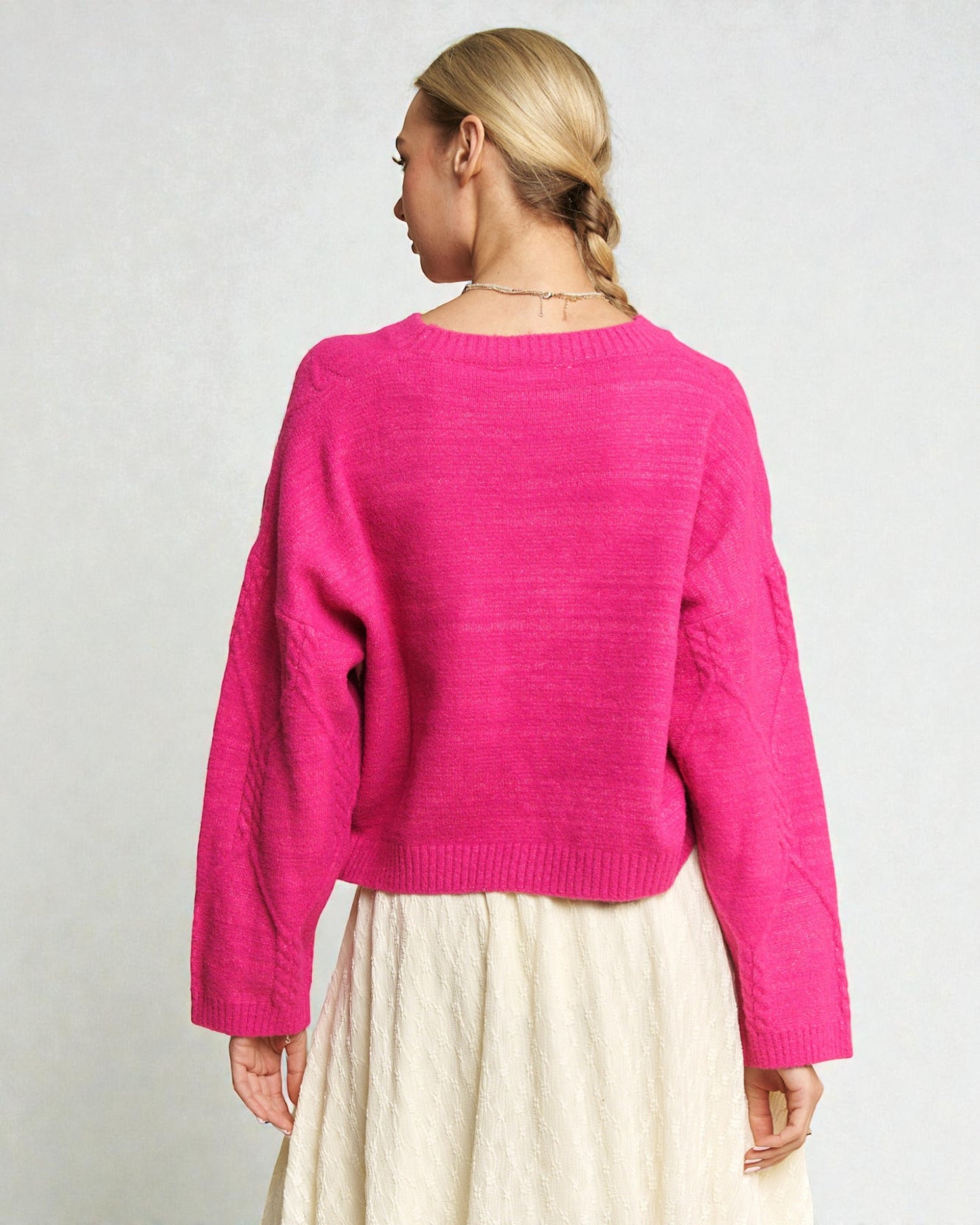 Person wearing a bright pink sweater on a plain background