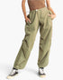 A person wearing loose olive green drawstring cargo-style pants with side pockets, paired with a brown top and black-and-white sneakers, against a plain light background.