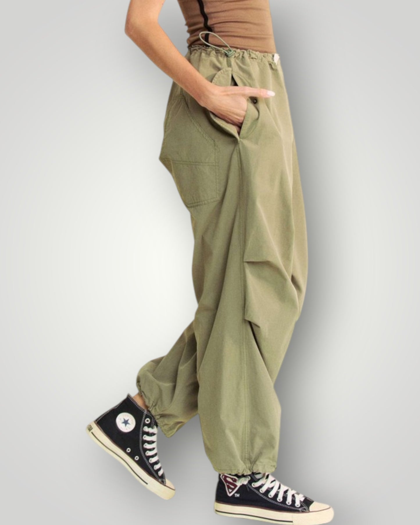 Person wearing olive green cargo pants and black high-top sneakers on a gray background