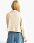 A woman shown from the back wearing a light beige cropped knit cardigan with wide draped sleeves and blue jeans, against a plain white background.