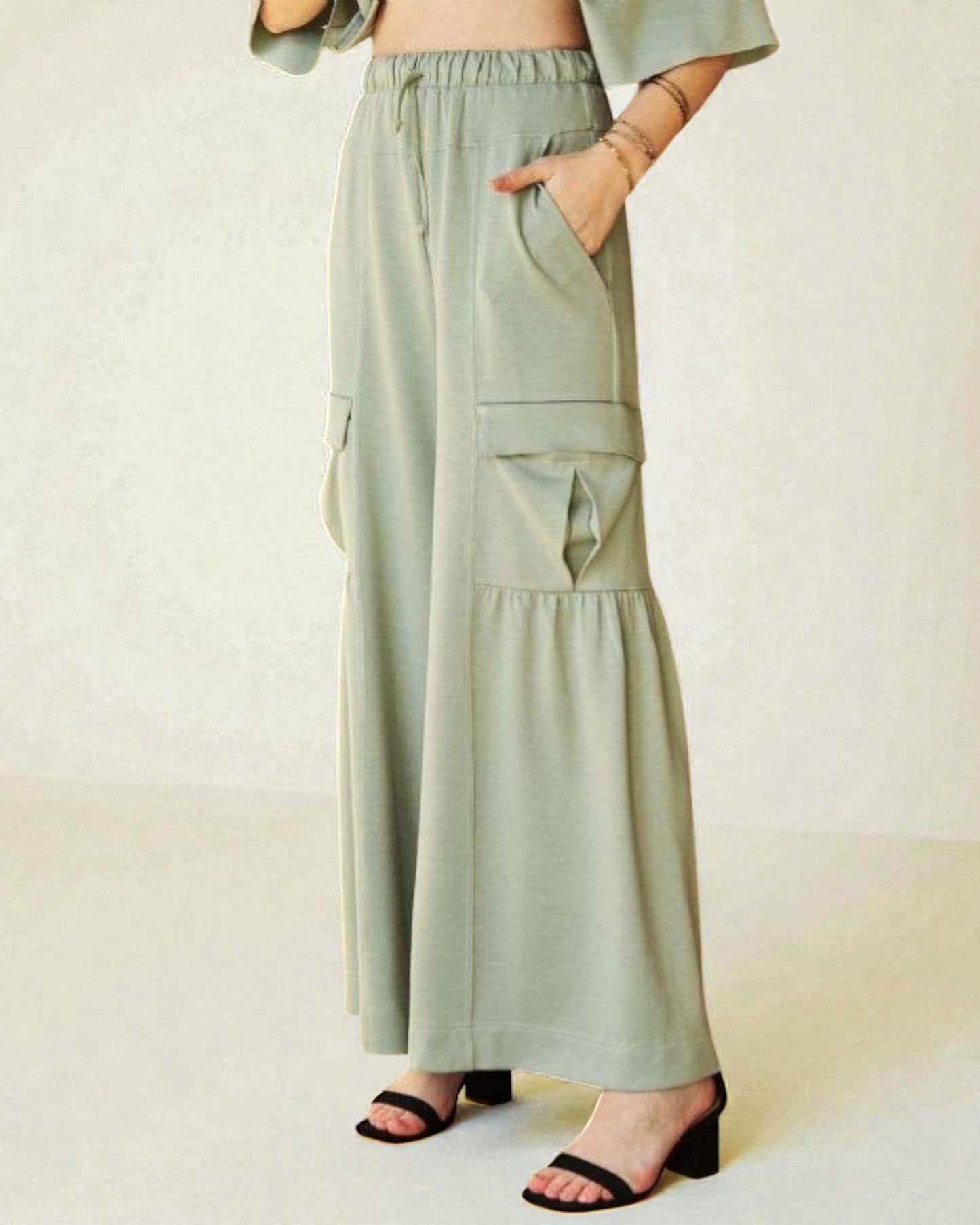 Person wearing light green wide-leg pants with a plain background