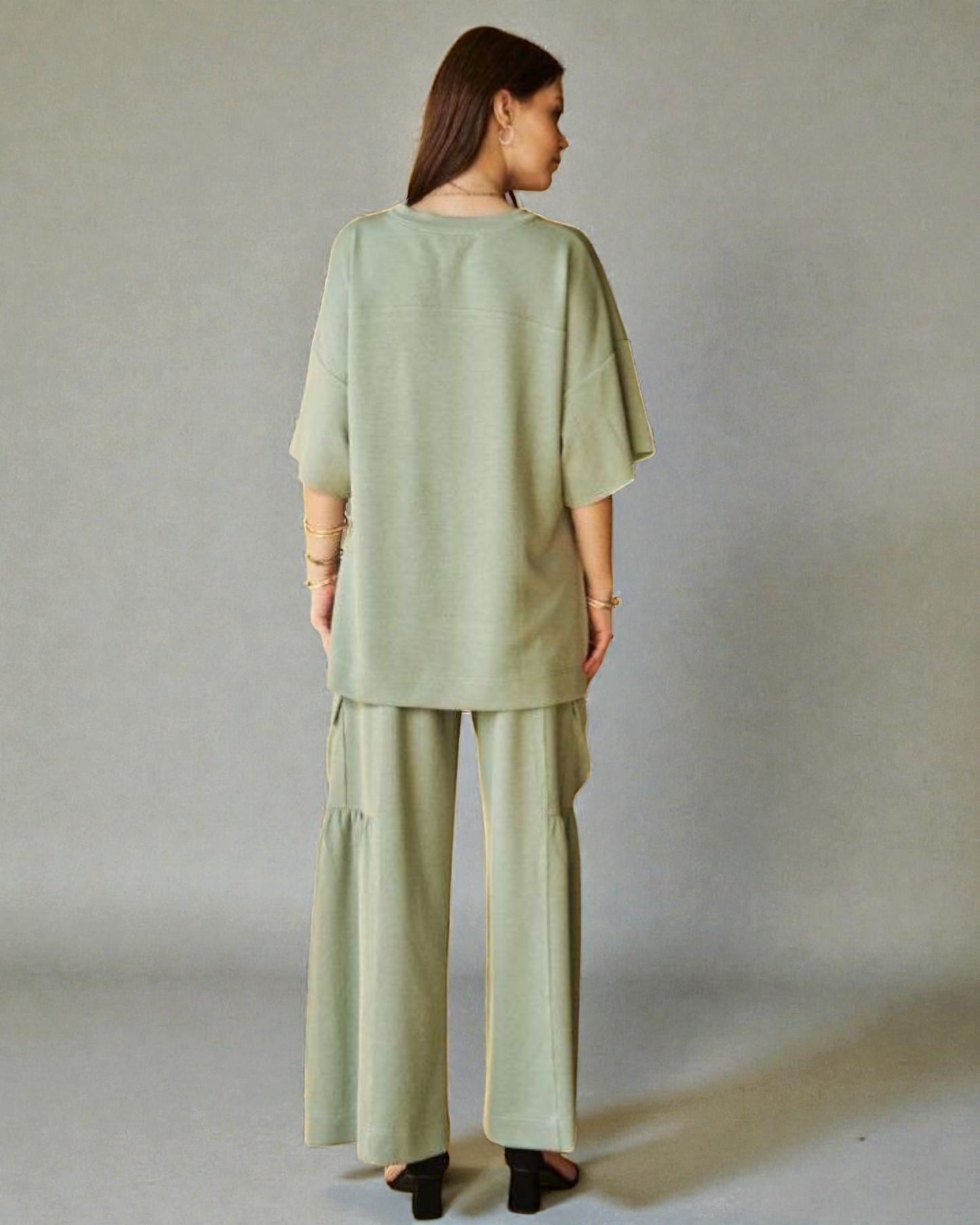 Woman wearing a green outfit standing against a plain background