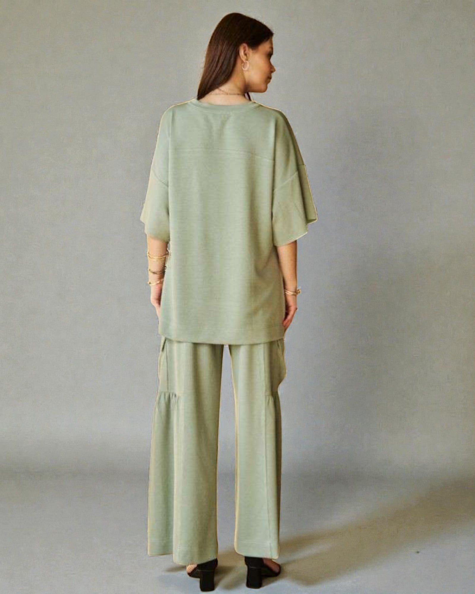 Woman wearing a green outfit standing against a plain background