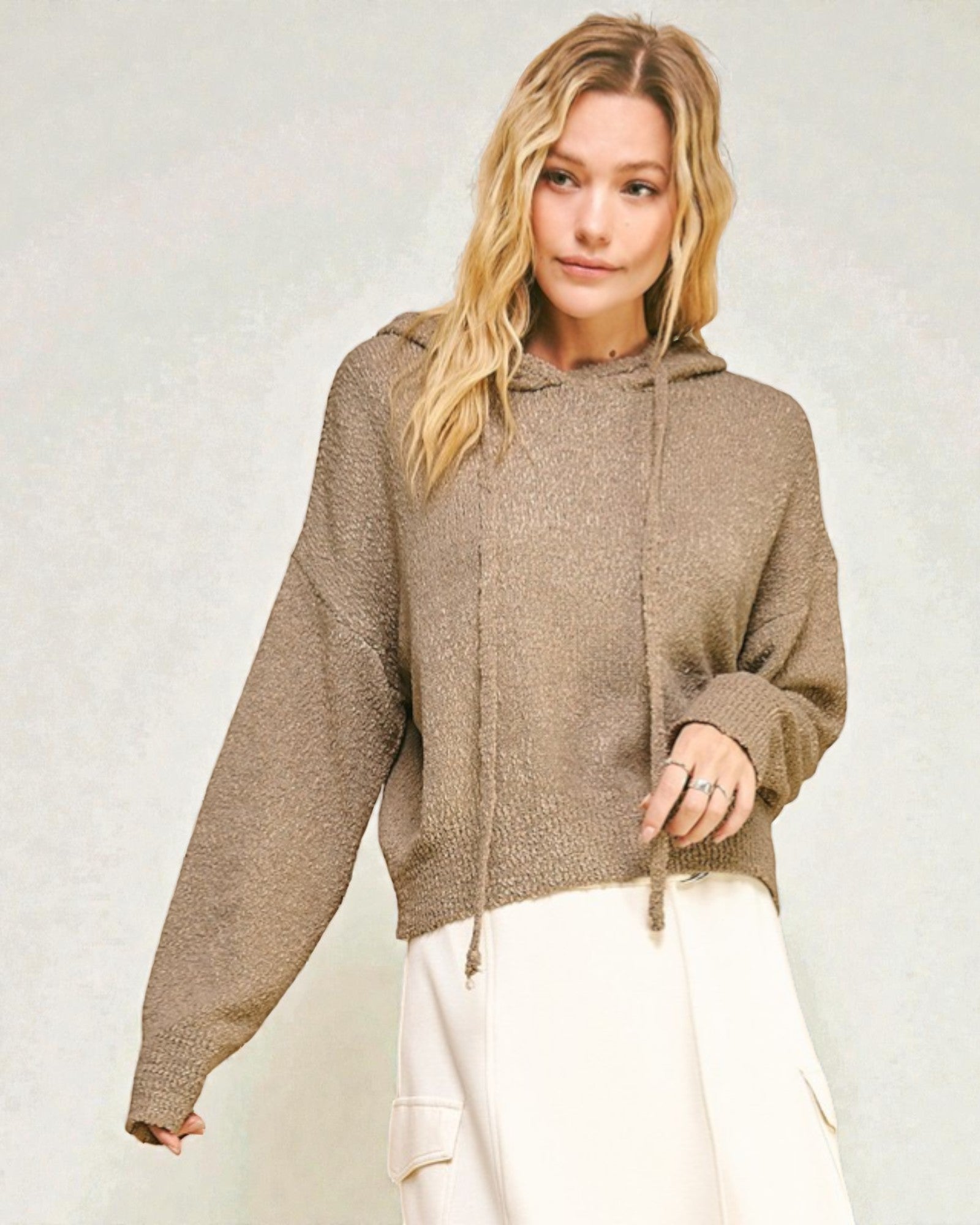 Woman wearing a brown hoodie against a plain background