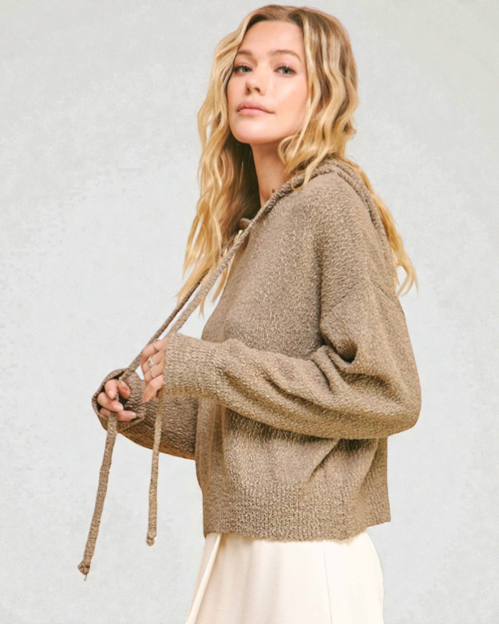 Woman wearing a beige sweater against a plain background