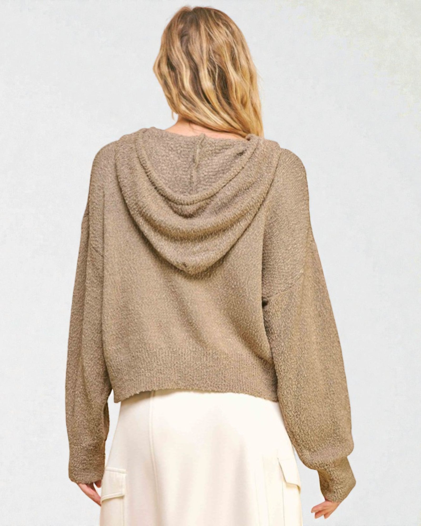 Person wearing a beige hoodie from behind on a plain background