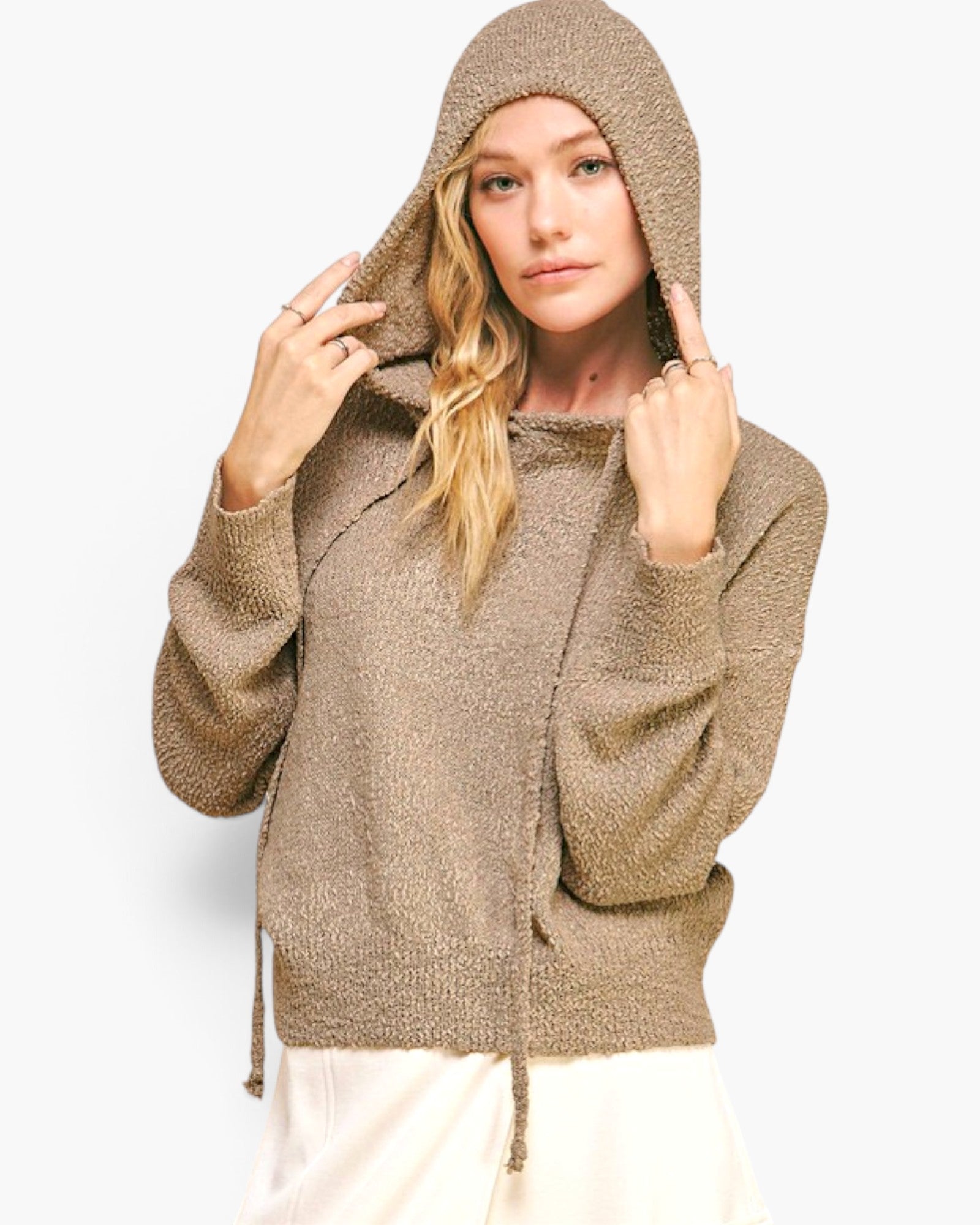 A woman wearing a textured, heathered taupe-brown hooded pullover sweater with drawstrings, posing against a light gray studio background.