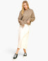 A woman modeling a cropped taupe knit hoodie with a drawstring, paired with a cream midi skirt and black low-top sneakers, against a plain white studio background.